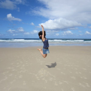 Sprachreisen für junge Erwachsene Frau am Strand spring in die Luft