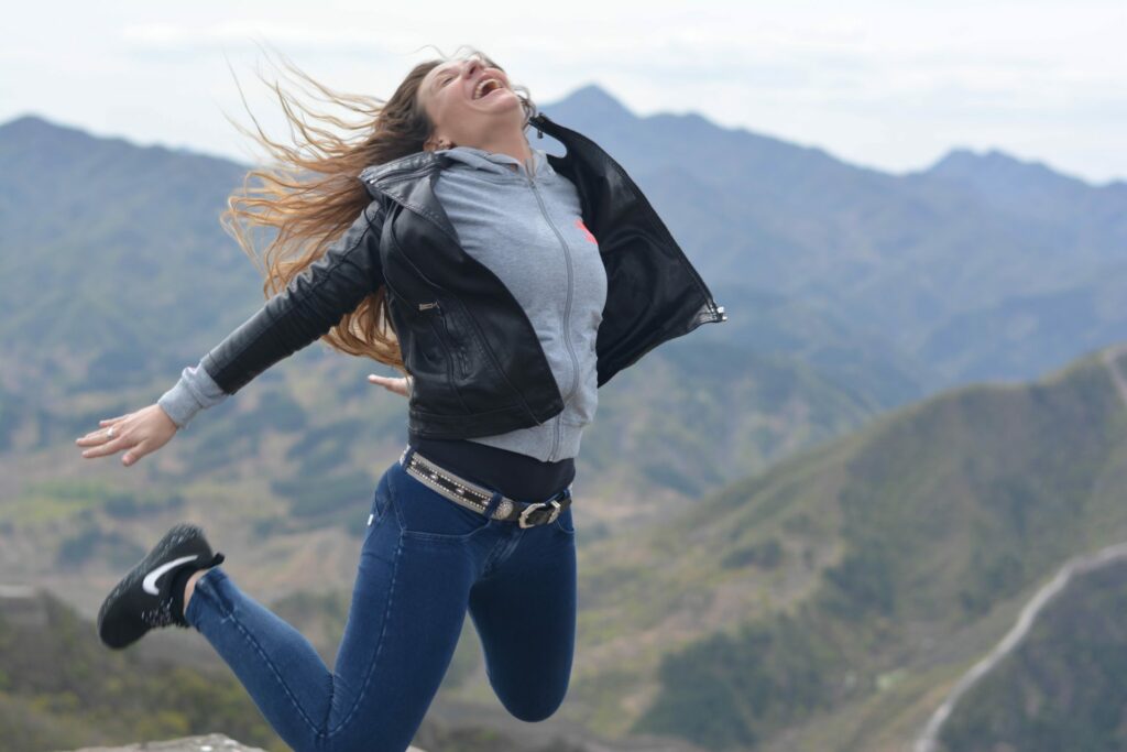 A student jumping with joy against a mountainous landscape backdrop
