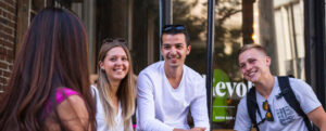 Four young people chatting and laughing together on a sunny urban street
